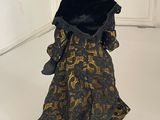 a black and gold dress and hat on a white floor