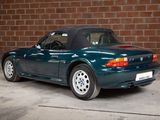 a picture of a blue sports car parked in front of a brick wall