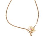 un collier en or orné d'une fleur et d'un pompon sur fond blanc