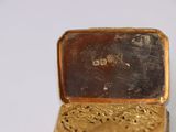 a gold box that has a small gold object inside of it