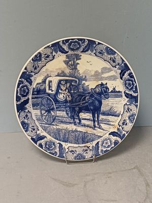 a blue and white plate with a horse drawn carriage on it