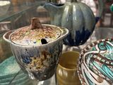 a glass display case with a teapot and bowls on it