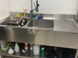 un évier au milieu d'une cuisine où le sol est jonché d'objets en désordre