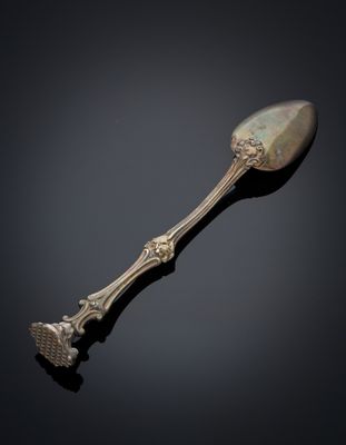 an antique silver spoon on a black surface with a black background
