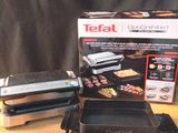 a box of food on a table with a grill and tongs