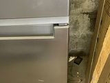 an image of a silver refrigerator in a dirty room