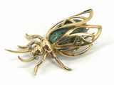 a close up of a gold insect broochle on a white background