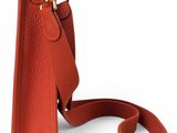 an orange leather handbag with a strap on a white background