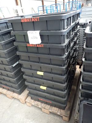 de nombreux conteneurs en plastique noir empilés sur des palettes dans un entrepôt