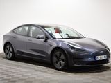 a grey tesla model 3 parked on a checkered floor