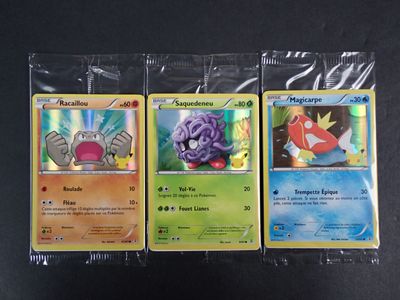 Trois cartes Pokémon sont posées sur une table noire.