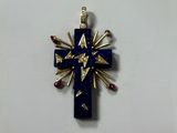 un gros plan d'une croix sur une surface blanche, ornée de pierres rouges et bleues