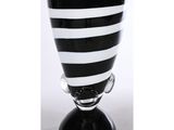 un vase en verre rayé noir et blanc posé sur un socle