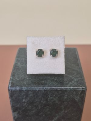 a close up of a pair of green stone earrings on a marble block