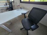 a white desk with a black chair in front of a window