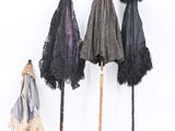 three umbrellas are lined up against a white wall with black lace