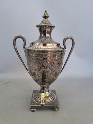 an antique silver plated urn with a bird on it