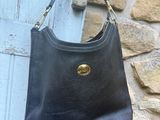 un sac à main en cuir noir accroché à un mur en pierre près d'une porte bleue