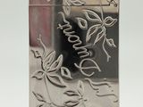 une image représentant un briquet argenté orné d'un motif de feuilles