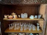 a wooden cabinet with many glasses and plates on it