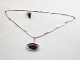 a close up of a necklace with a red stone on it