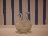a clear glass vase with a curved handle on a table