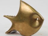 brass fish sculpture on a white surface with a white background