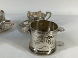 two silverplated cups and saucers with spoons on a white surface