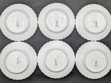 six white plates with designs on them sit on a table