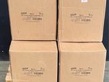 Plusieurs cartons sont empilés sur des palettes devant un mur noir.
