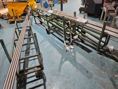 many steel pipes that are on the floor in a factory