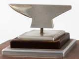 sculpture of an anvil on a wooden base on a white background