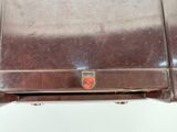 a brown suitcase that has a red emblem on it