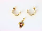 deux paires de boucles d'oreilles et un pendentif posés sur une surface blanche