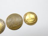 trois pièces d'or posées les unes à côté des autres sur une surface blanche