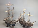pair of wooden model ships sitting on top of a wooden stand