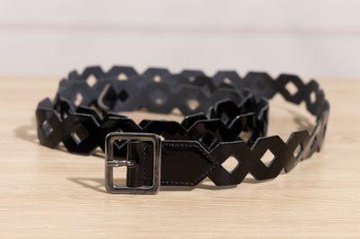 un gros plan d'une ceinture noire posée sur une table en bois