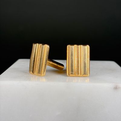 gold plated cufflinks on a white marble block