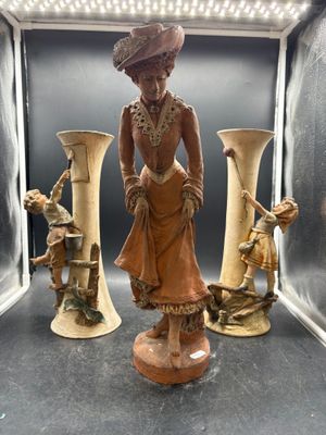 a statue of a woman in a dress and three vases