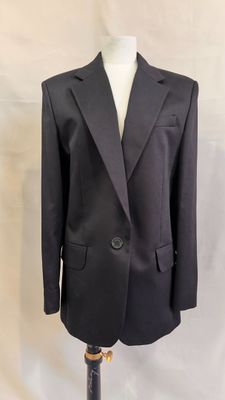 a black suit on a mannequin stand with a white background