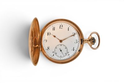 une montre de poche en or sur une surface blanche avec un fond blanc
