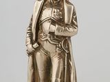 an antique silver figurine of a man with a hat and coat