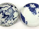 pair of blue and white plates with dragon designs on them