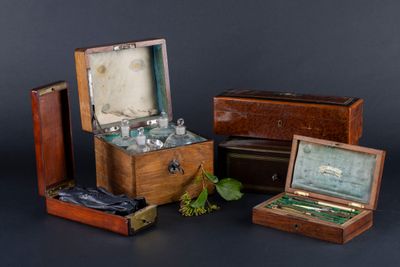 trois boîtes en bois contenant des bouteilles en verre, sur fond noir