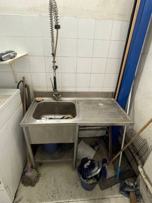 a sink in the corner of a kitchen with a trash can