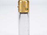 une petite bouteille en verre avec un bouchon doré et un bouchon vert