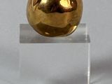 une pomme dorée posée sur un socle transparent