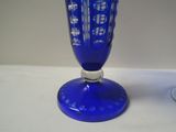 a blue glass vase sitting on a table next to a wine glass