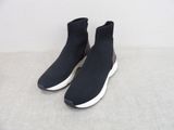 une paire de baskets noires à semelles blanches posées sur une surface grise