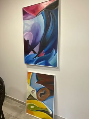 des tableaux accrochés au mur dans une pièce où se trouvent une table et des chaises
